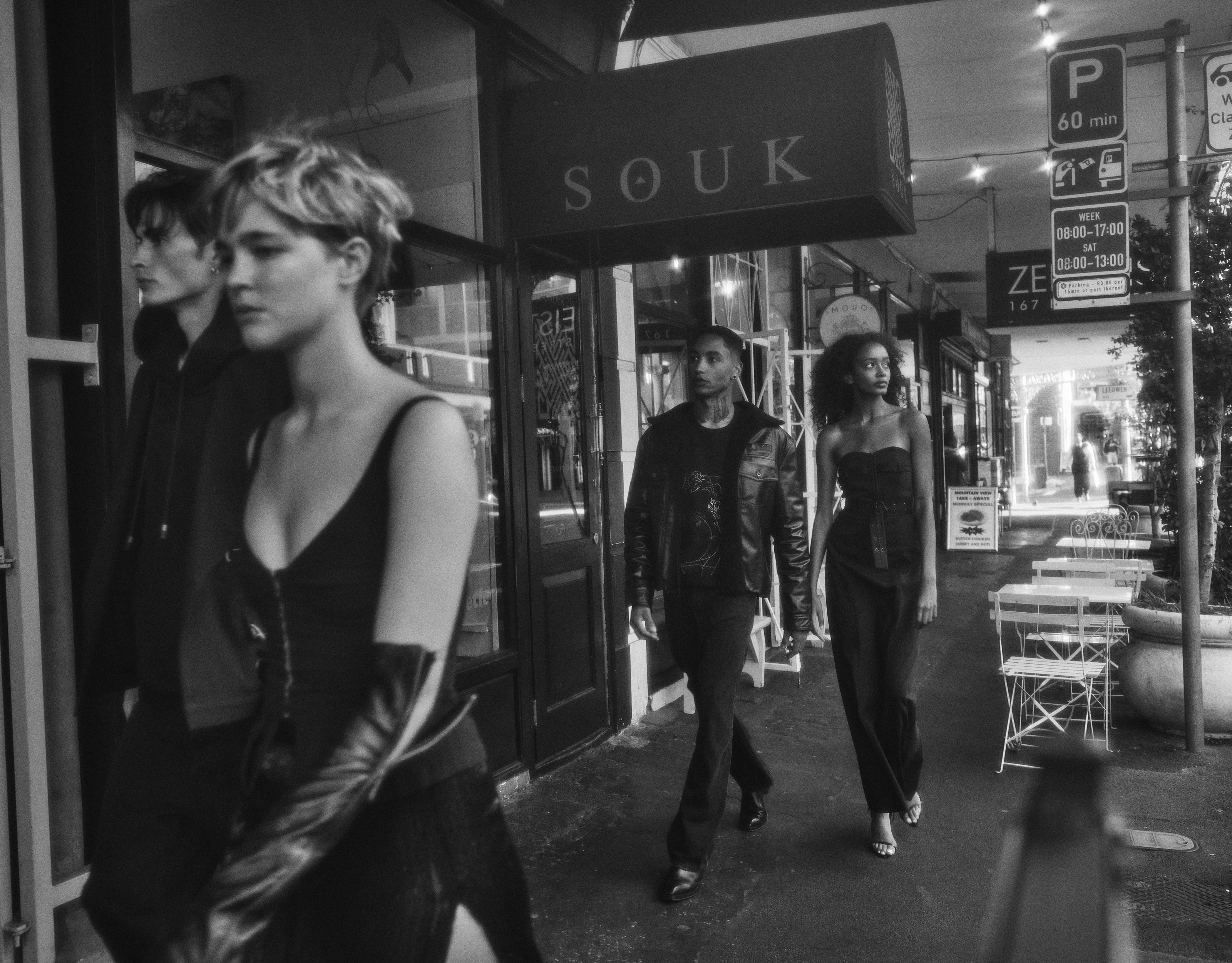 A bustling street scene depicted in black and white, with a group of individuals walking.